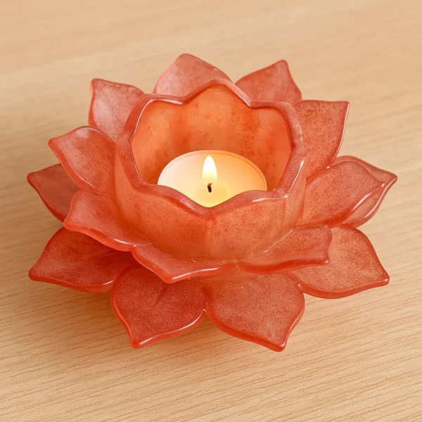Red lotus-shaped candle holder with a small lit tea light on a wooden surface, emitting a warm glow