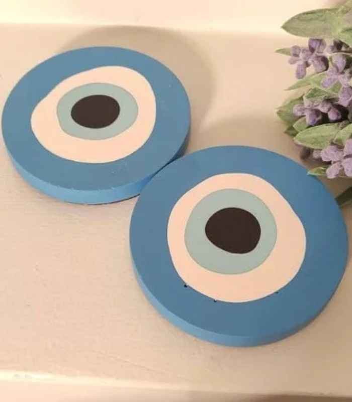 Two round blue decorative pieces with concentric rings (white, light blue, black center) on a white surface near lavender sprigs.
